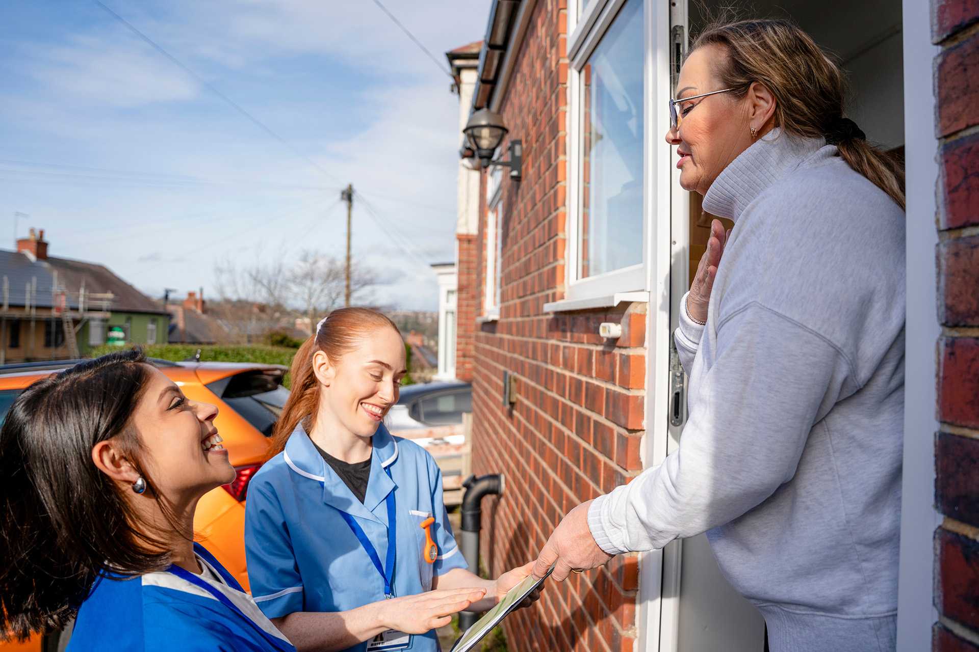Two females social service workers outside a carer's front door, showing how a care needs assessment can provide help for carers in England and Wales.