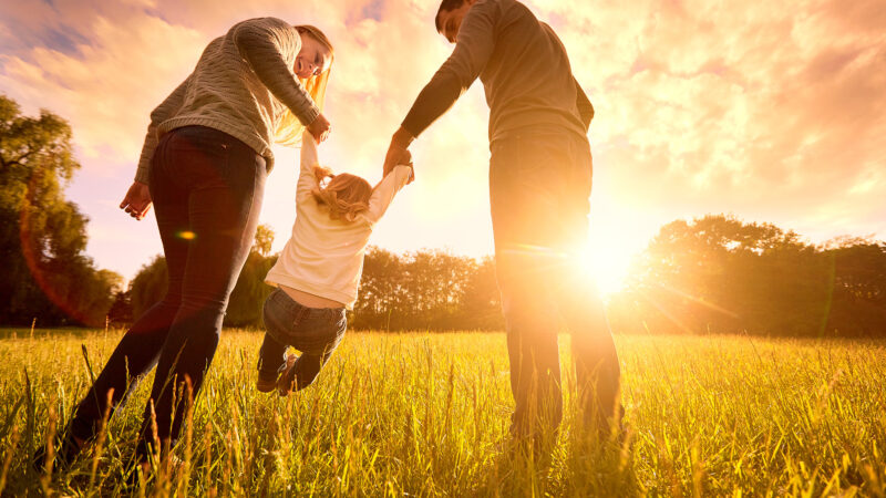 Parents swinging a toddler in the air, denoting family support after leaving armed forces service.
