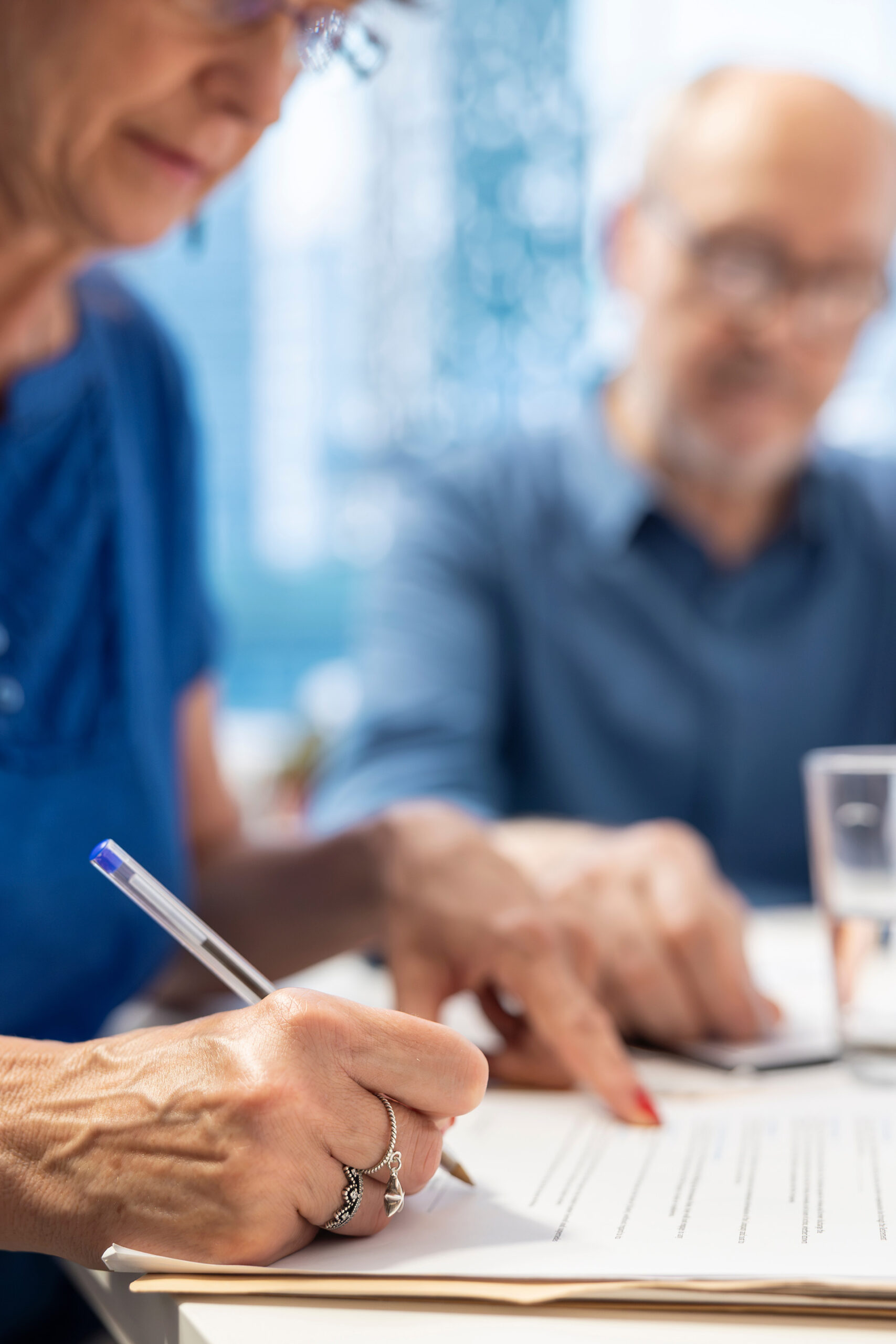 An elderly couple at a kitchen table looking at armed forces pensions advice.