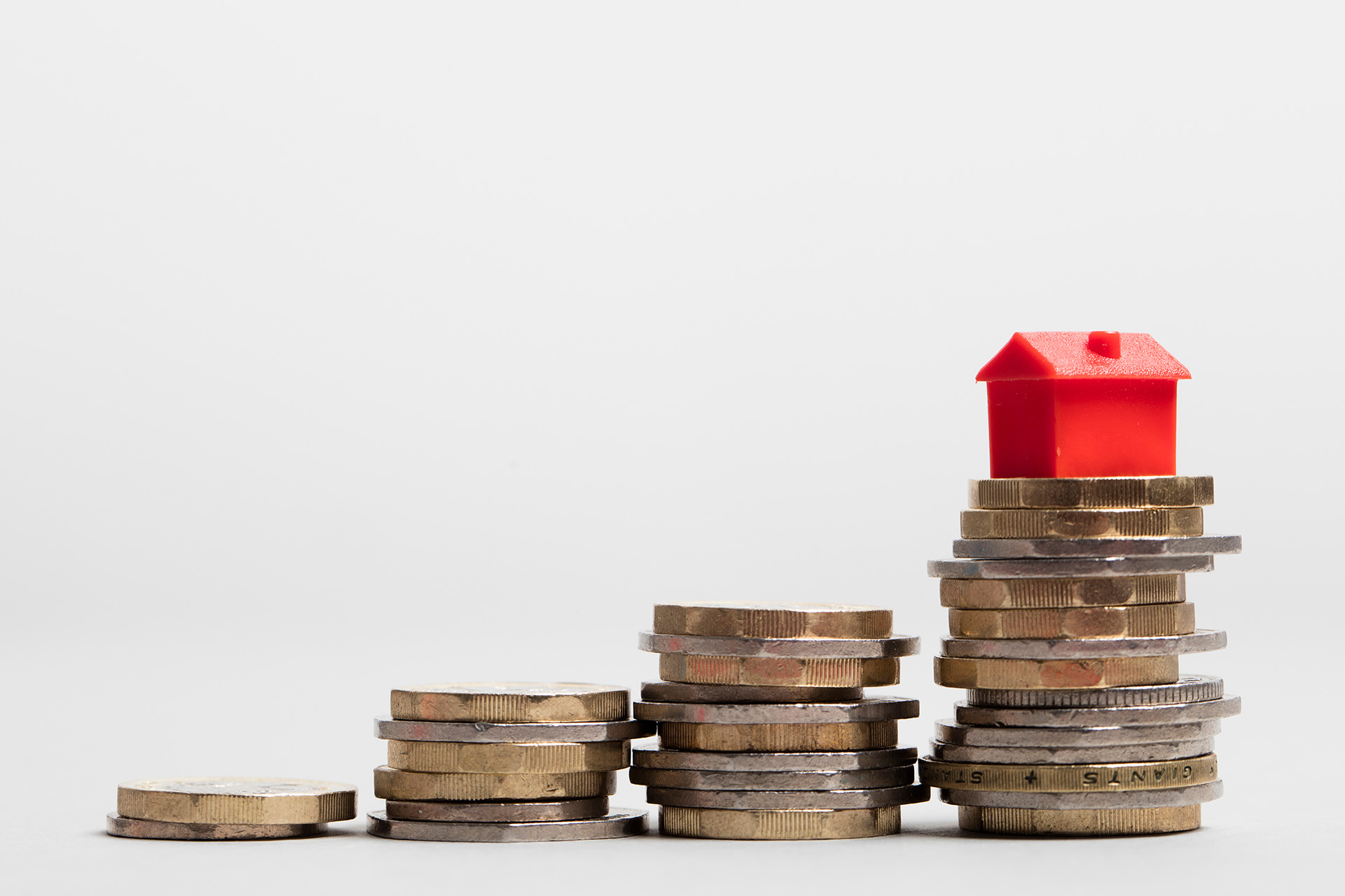 A toy house standing on a stack of coins, showing how serving personnel can get help to buy a home in England through the Forces Help to buy scheme.