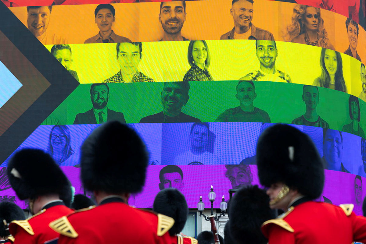 A parade before a rainbow-coloured motif in the background, highlighting the contribution LGBT+ veterans have made to the UK armed forces.